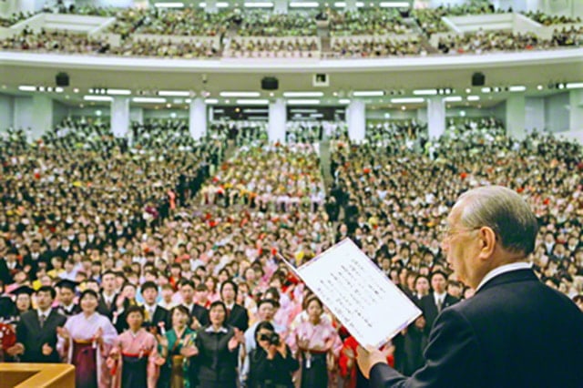 画像　創価大学池田記念講堂で学生とともに歌を歌う池田大作先生