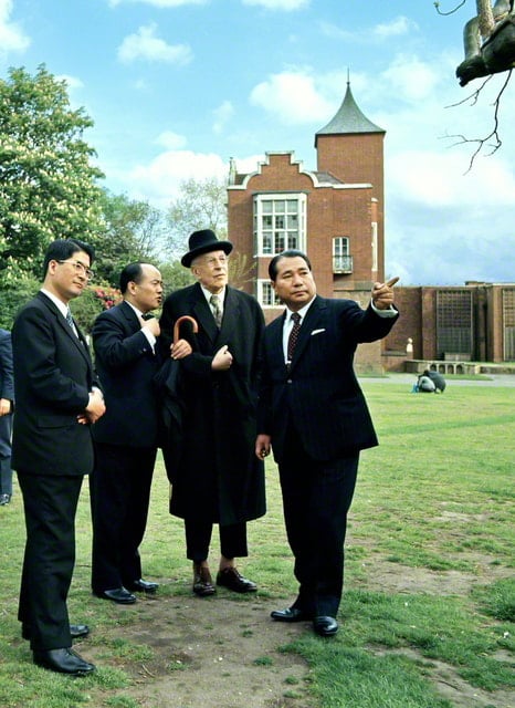 画像・黒色の帽子にコート姿のトインビー博士と並ぶ池田先生は左手でなにかを指差している