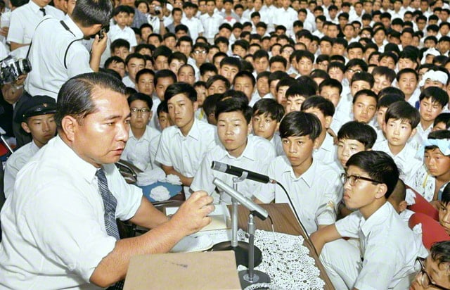 画像・池田先生を囲む学園生。ぎっしりと詰めて座っている